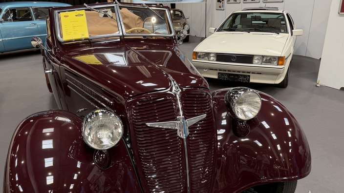 Ein weinroter Oldtimer des Herstellers Adler in einer Messehalle.
