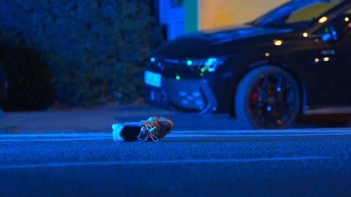 Ein Schuh liegt auf einer Fahrbahn.