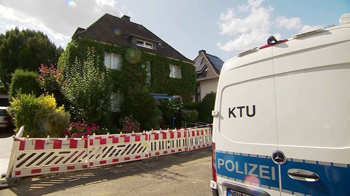 Ein Auto von der Spurensicherung der Polizei steht vor einem Haus.
