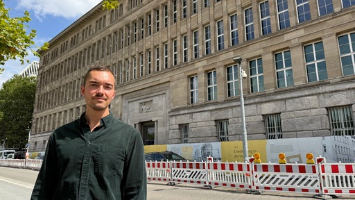 Mann in schwarzem Hemd vor historischem Gebäude