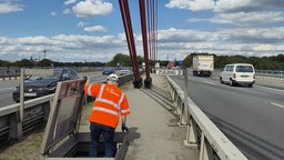 Ein Besucher der Führung klettert durch eine Bodenklappe auf eine Fläche zwischen den beiden Fahrbahnen auf der Fleher Autobahnbrücke.