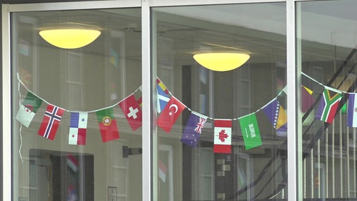 Ein Fenster, in dem viele bunte Flaggen verschiedener Länder hängen