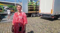 Eine Frau in einem roten Kleid steht auf dem Gelände der Rheinkirmes