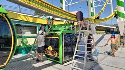 Die Gondeln werden am Riesenrad auf der Rheinkirmes montiert