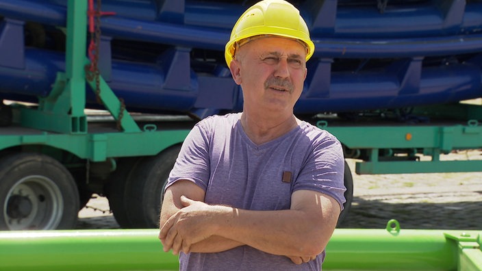 Ein Arbeiter mit gelbem Helm arbeitet am Aufbau der Achterbahn