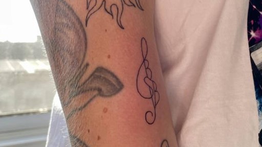 Ein Notenschlüssel Tattoo auf dem Arm einer Frau