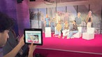 Im Vordergrund hält eine Person ein Tablet mit offener Kamera. Rechts daneben sitzen 3 Frauen vor Papp- Aufstellern der Backstreet- Boys