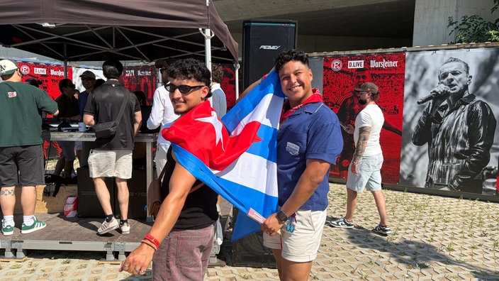 Zwei Männer halten eine Flagge hoch.