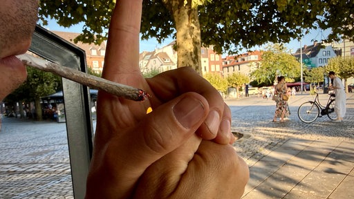 Ein Mann zündet sich einen Joint in Düsseldorf an