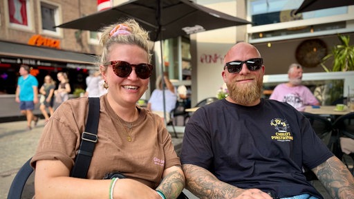 Eine Frau und ein Mann sitzen vor einem Café in Düsseldorf