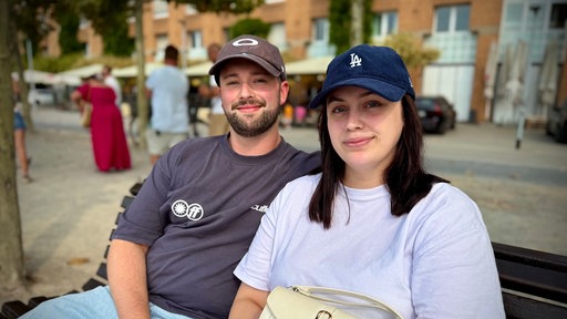 Eine Frau und ein Mann sitzen am Düsseldorfer Rheinufer