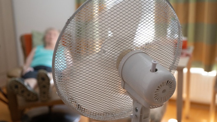 Seniorin sitzt vor einem Ventilator