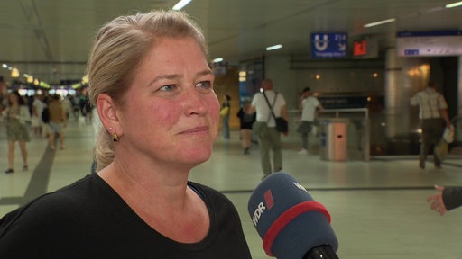 Eine blonde Frau steht im Düsseldorfer Hauptbahnhof 