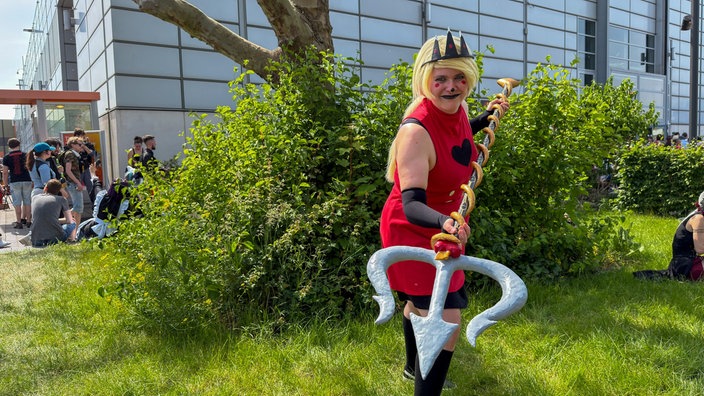 Eine Frau im Cosplay von Charlie Morgenstern aus der Serie Hazbin Hotel.