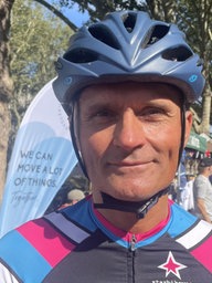 Mann mit Fahrradhelm und Sportshirt blickt direkt in die Kamera