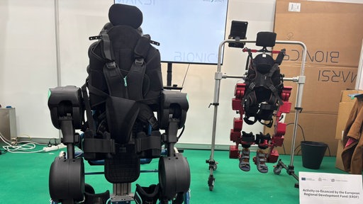 Zwei Exoskelettmodelle an einem Stand auf der Rehacare in Düsseldorf
