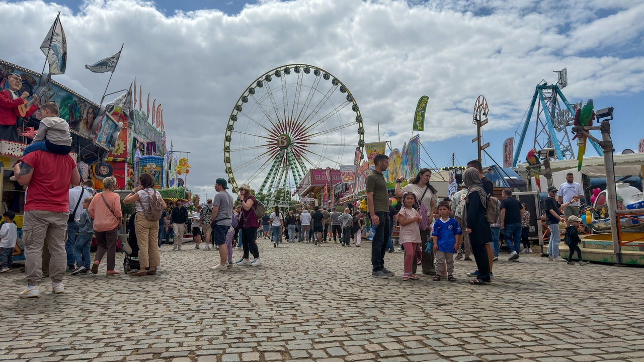 Imbissbuden und Fahrgeschäfte auf der Düsseldorfer Rheinkirmes mit Blick aufs Riesenrad