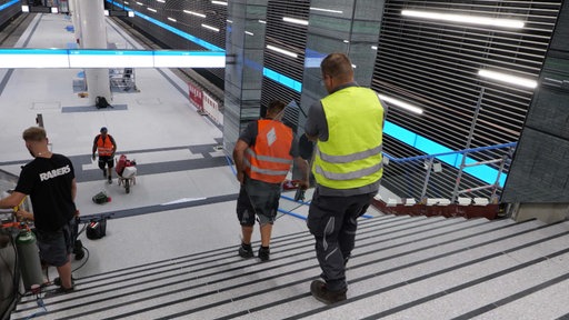 Arbeiter bei den letzten Handgriffen zur Fertigstellung des Flughafenbahnhofs
