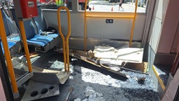 Im Passagierraum der Straßenbahn liegt Verkleidung und zerbrochene Scherben des Fensters auf dem Boden. 