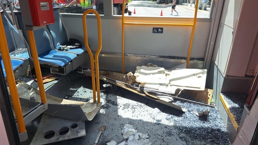 Im Passagierraum der Straßenbahn liegt Verkleidung und zerbrochene Scherben des Fensters auf dem Boden. 