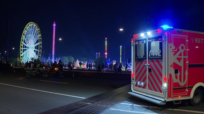 Ein Rettungswagen in der Dunkelheit vor der leuchtenden Kirmes-Kulisse