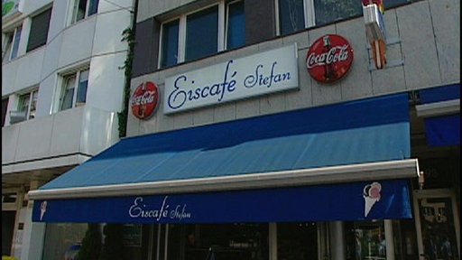 Fassade Eines Eiscafés. Das Schild liest "Eiscafé Stefan". Farbe und Qualität des Bildes indizieren, dass es sich um eine ältere Aufnahme handelt.