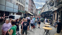 Eine Menschenschlange steht in einer Straße der Düsseldorfer Innenstadt. Sie warten vor einem Fanshop.