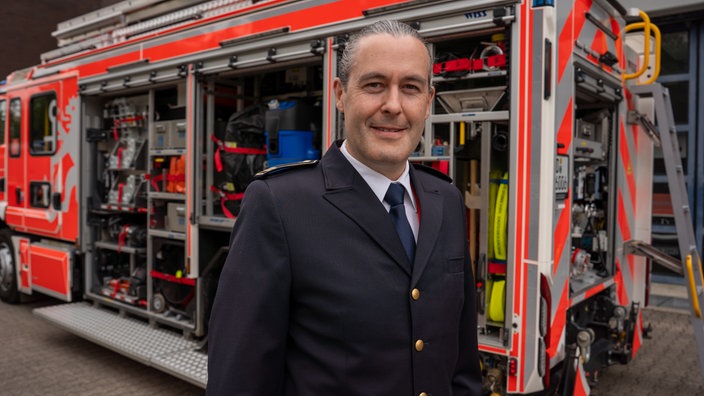 Christoph Schäfer steht vor einem Einsatzfahrzeug der Feuerwehr.