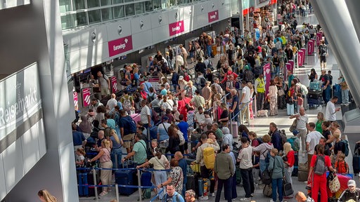 An den Gepäckschaltern am Flughafen Düsseldorf stehen viele Menschen an.