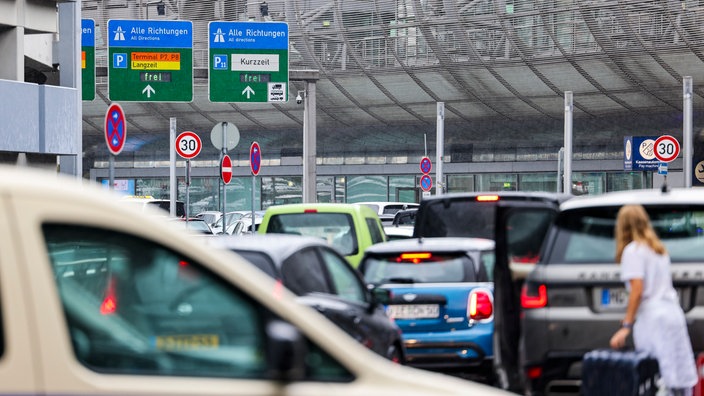 Vor einem Flughafengebäude stehen Autos im Stau