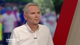 Ein Mann steht mit weißem Hemd im Studio der Lokalzeit Düsseldorf.