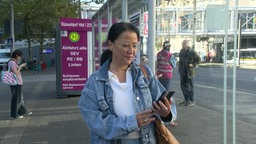 Heike Horal steht an der Bushaltestelle und schaut aufs Handy