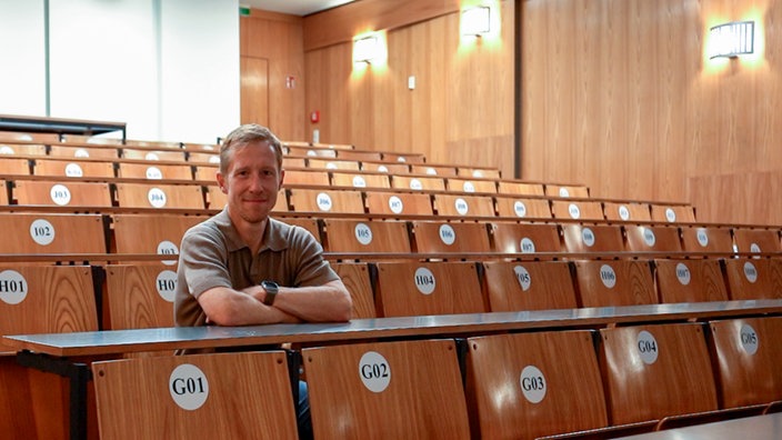 Marc Ziegele sitzt in einem Hörsaal der Heinrich-Heine-Universität.