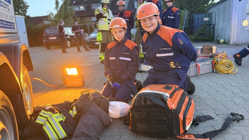 Zwei Mitglieder der Jugendfeuerwehr vor einer Dummy-Puppe kniend.