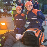 Zwei Mitglieder der Jugendfeuerwehr vor einer Dummy-Puppe kniend.