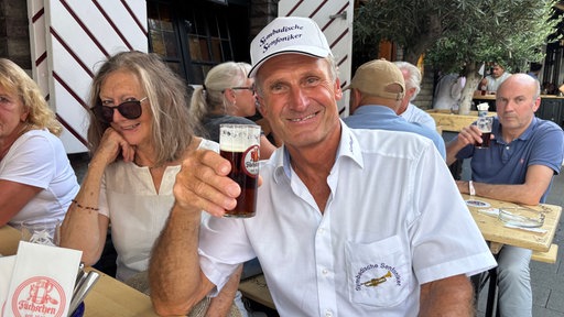 Gast Manni Schyle sitzt mit mehreren Leuten im Brauhaus und trinkt sein Altbier.