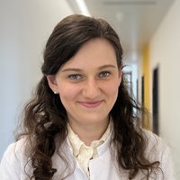 Eine junge Frau mit langen, braunen Haaren schaut in die Kamera.
