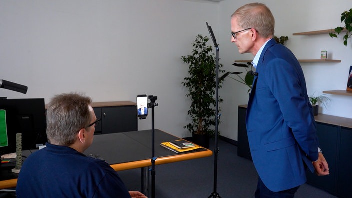 Gerold Wenzens, Bürgermeister von Langenfeld, guckt sich seine Videoaufnahme noch einmal auf dem Handy an.