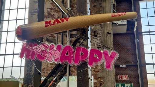 Aufblasbarer Riesenjoint über einem pinken "Highhappy" Schild 