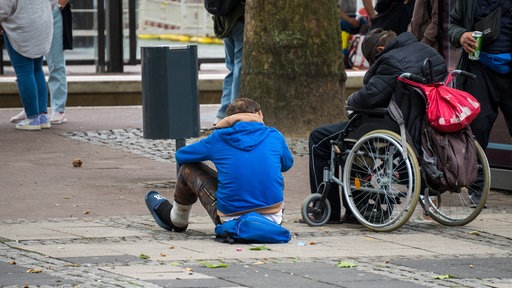 Drogenkonsumenten sitzen am Kölner Neumarkt. Ihre Gesichter sind nicht zu erkennen.