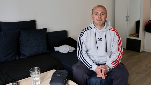 ein Mann sitzt auf dem Sofa und lächelt in die Kamera