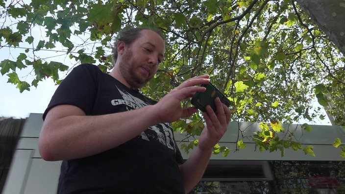 Konzertbesucher Thomas Wolter aus Köln hat sein Handy in der Hand und schaut sich Fotos vom Konzert an