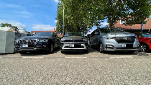 Autos mit auswärtigen Kennzeichen stehen auf einem Parkplatz in Düsseldorf Lichtenbroich