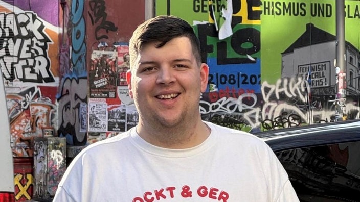 Ein junger Mann schaut in die Kamera und lacht