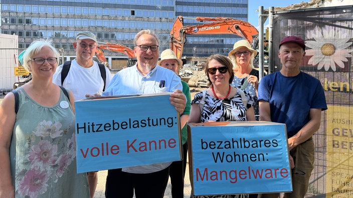 Anwohner protestieren vor Ort gegen die neuen Pläne. Sie stehen mit Plakaten vor der Baustelle.
