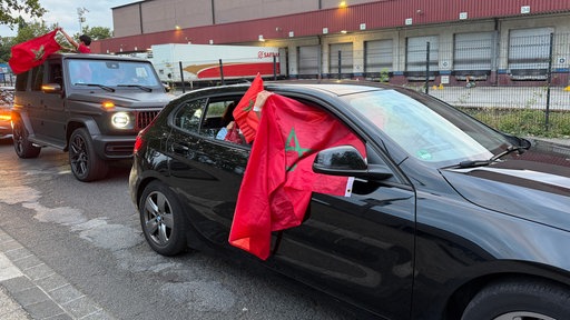 Zwei Autos mit marokkanischen Flaggen starten zu einem Auto-Korso.