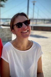 Eine Frau sitzt am Rhein und lächelt