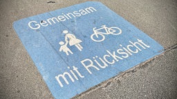 Ein Schild auf einem Boden zeigt Fußgänger und ein Fahrrad