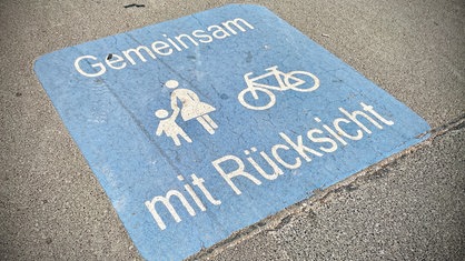 Ein Schild auf einem Boden zeigt Fußgänger und ein Fahrrad