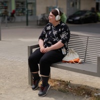 Can sitzt auf einer Parkbank und hört Musik.